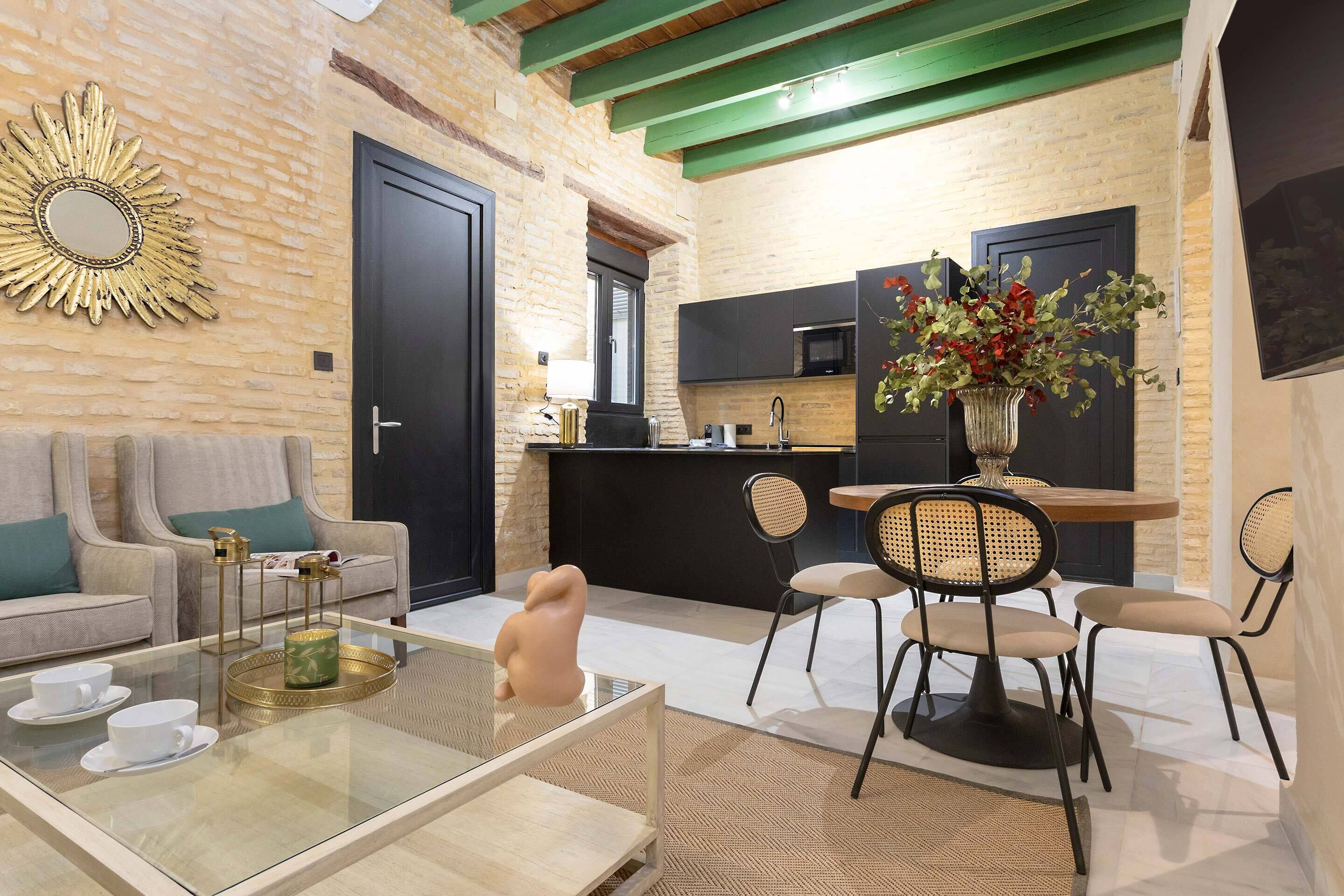 Een moderne woonkamer met een bank, salontafel en stoelen. In de achtergrond is een keuken met een eethoek zichtbaar.