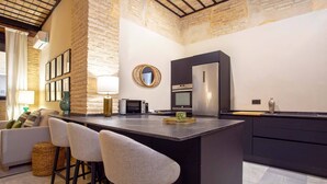 A modern kitchen with a central island, bar stools, a microwave, oven, and a refrigerator. - Genteel Home Acetres III (Seville)