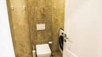 Un baño con inodoro, lavamanos y lavadora.