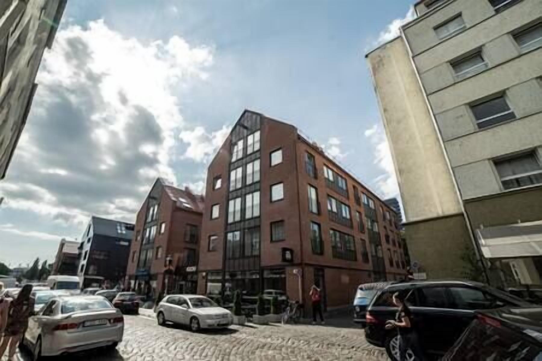 Un edificio de varios pisos con un diseño arquitectónico moderno, que combina fachadas de ladrillo y vidrio.