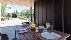 Een buiten eethoek met een houten tafel voor twee personen, compleet met borden, bestek en glazen.