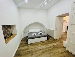 Ein kleines, modernes Schlafzimmer mit einem Bett, einem Nachttisch und einer Heizung.