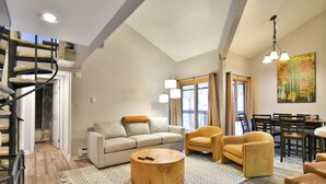 A spacious living area with a sofa, two armchairs, a coffee table, and a dining table with chairs. A staircase is visible in the background. - Wild Irishman Off-Piste Condo: Great Keystone Getaway (Keystone)