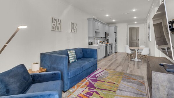 Una sala moderna con un sofá azul, una mesa de centro y un tapete colorido.