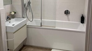 Un baño moderno con ducha envuelta en vidrio, una bañera independiente y un lavamanos.