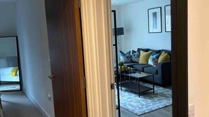 Una habitación con un espejo grande que refleja una sala de estar con sofá, mesa de centro y alfombra.