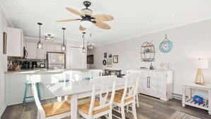 A modern kitchen with white cabinetry, a central island, and a ceiling fan.