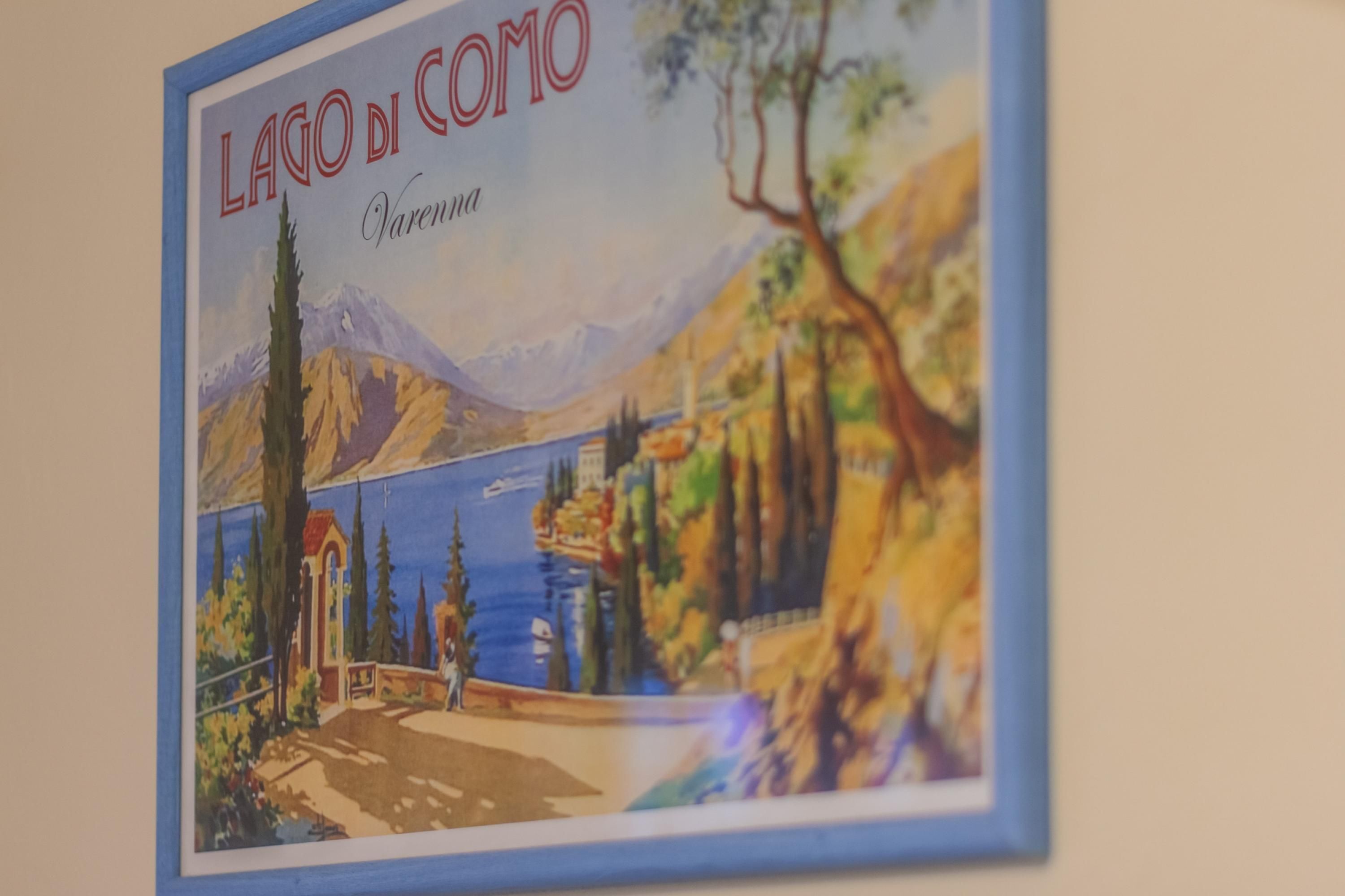A framed picture of Lago di Como with a mountain, trees, and a lake.