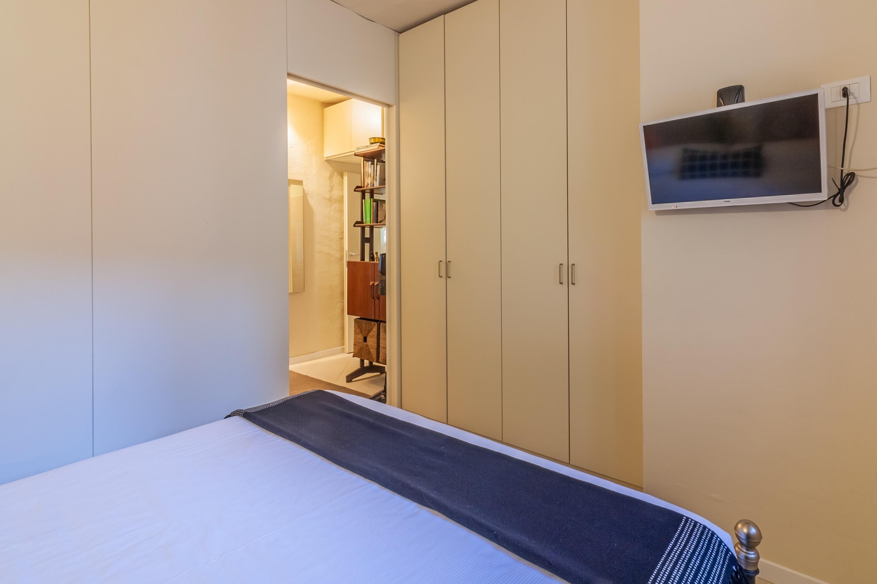 Une chambre à coucher comprenant un lit, une armoire et un téléviseur fixé au mur.
