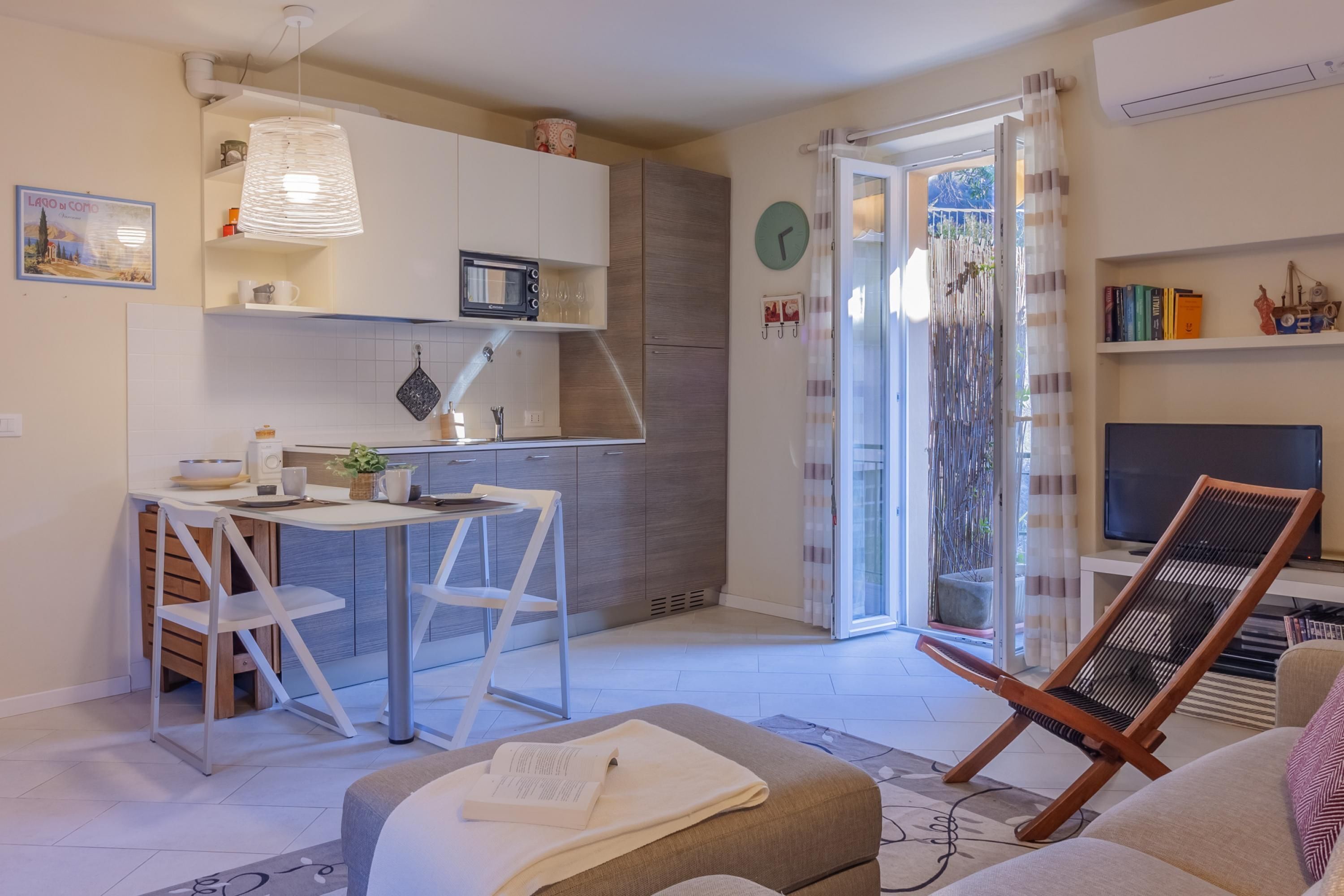 Um espaço compacto com cozinha compacta, área de jantar, sala de estar com sofá e poltrona, e televisão.