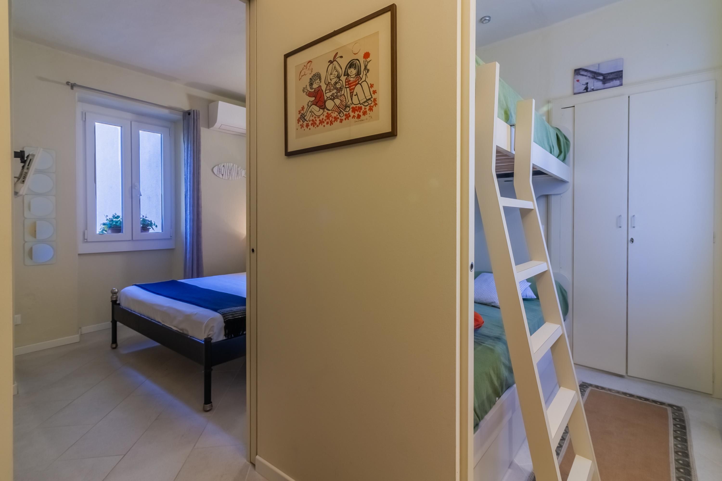 Ein Schlafzimmer mit einem Bett, einem Etagenbett, einem Fenster und einem gerahmten Bild an der Wand.