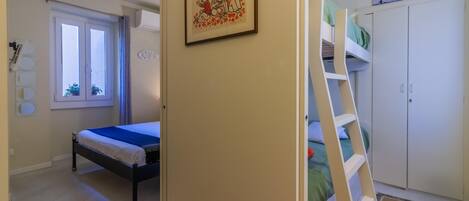 Ein Schlafzimmer mit einem Bett, einem Etagenbett, einem Fenster und einem gerahmten Bild an der Wand.
