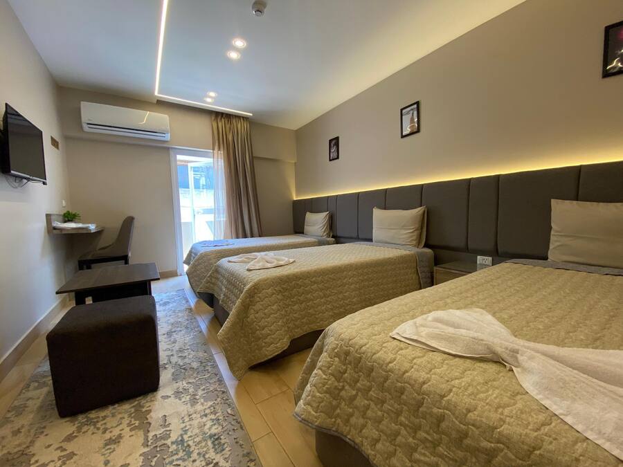 Habitación de hotel con dos camas, un escritorio, una silla, un televisor y un equipo de aire acondicionado.