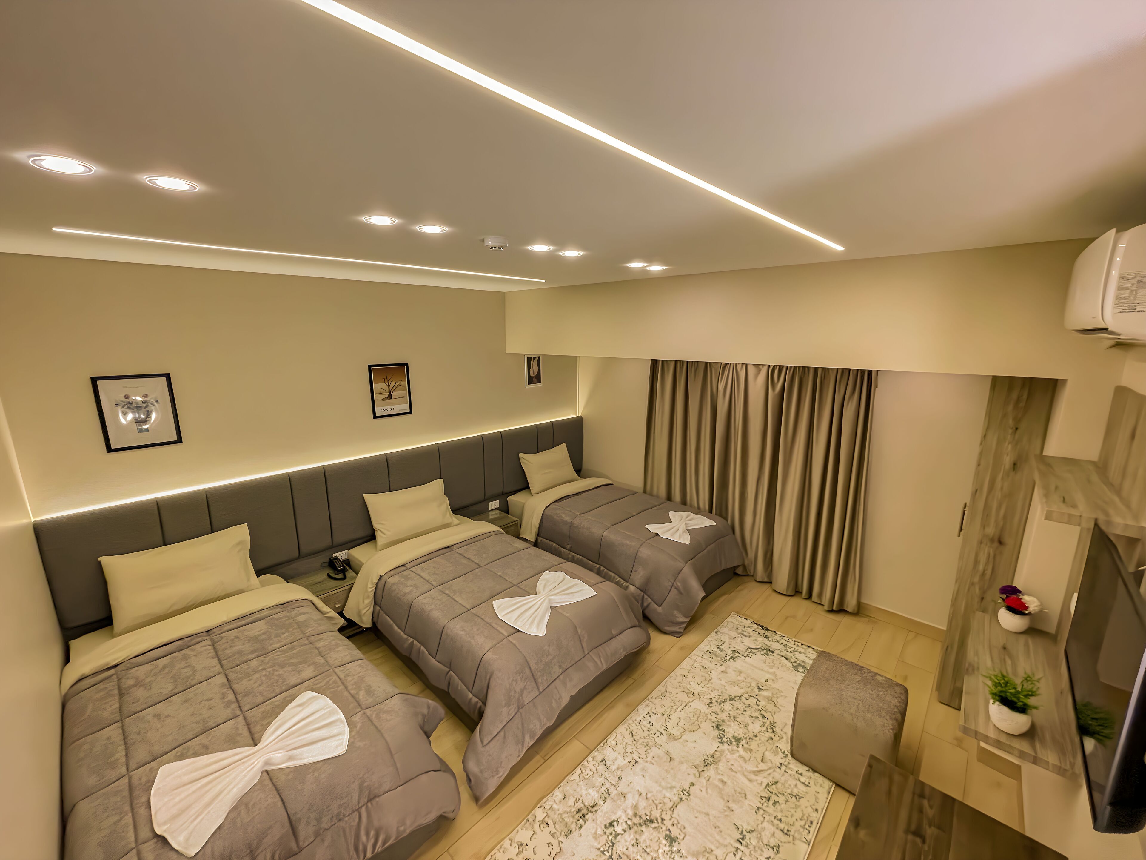 A modern hotel room with two beds, a flat-screen TV, a wooden sideboard, and a large window with curtains.