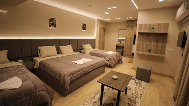 A modern hotel room with a large bed, a smaller bed, a wooden table, and a small stool. - Holy Sheet Plus, Boutique Hotel (Cairo)