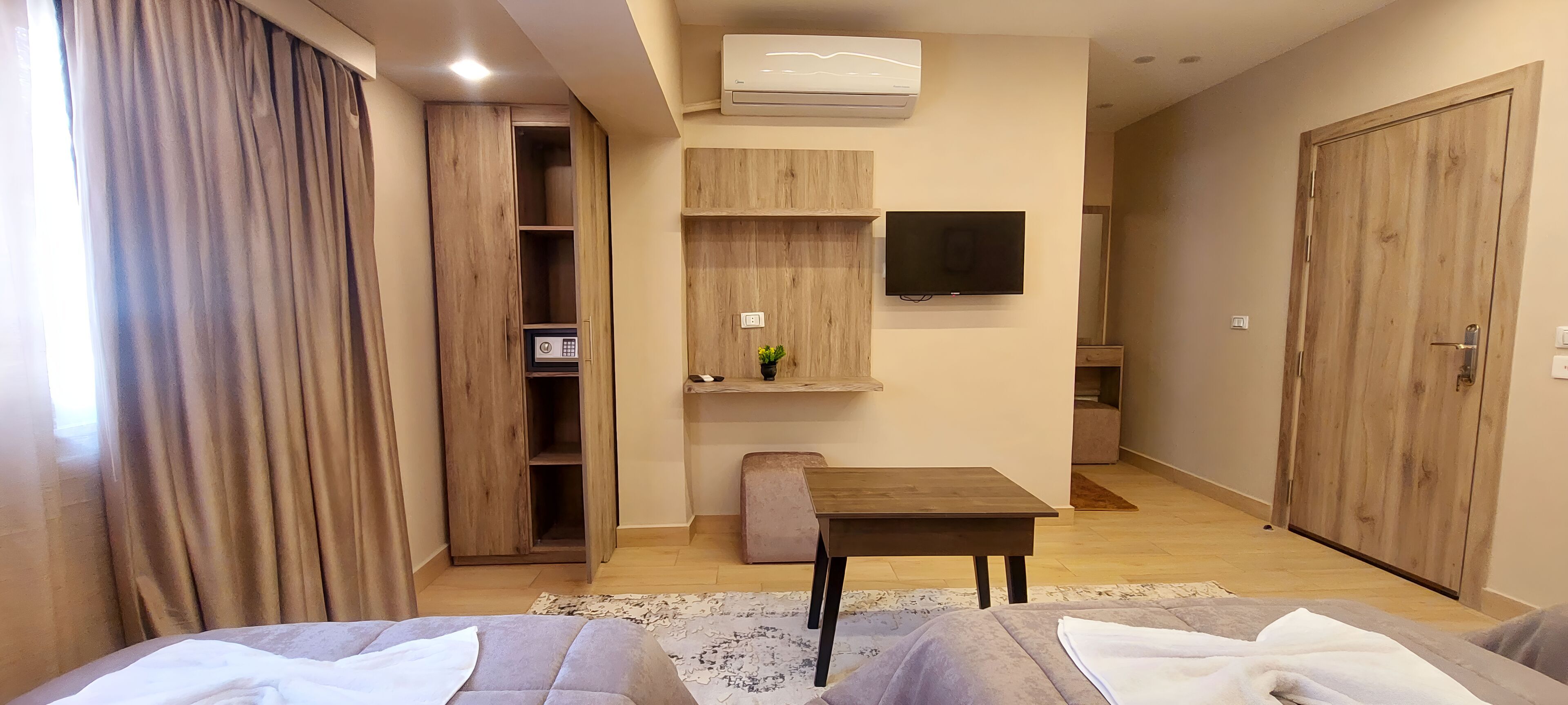 Una sala de estar moderna con un armario de madera, una mesita, un televisor y un sofá.