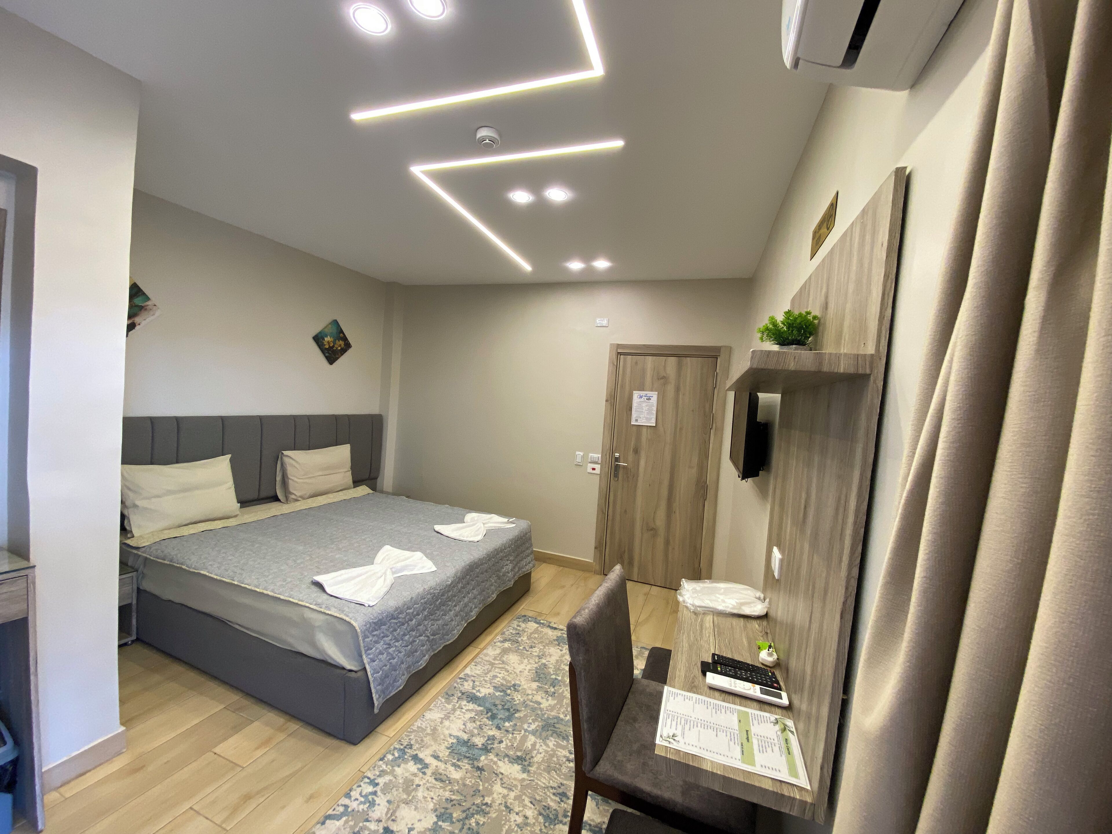 Een moderne hotelkamer met een bed, nachtkastje en een bureau met stoel.