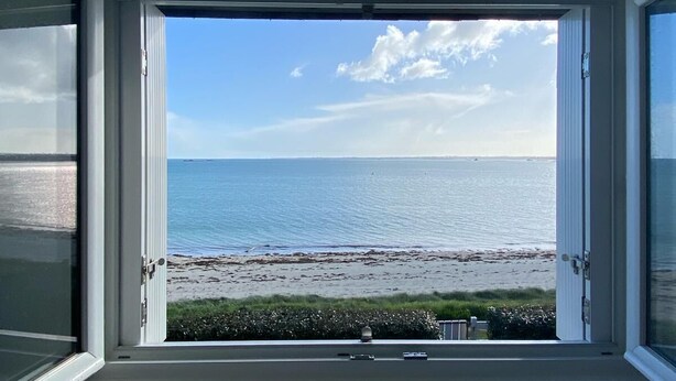 Una stanza con una grande finestra vista spiaggia e mare.