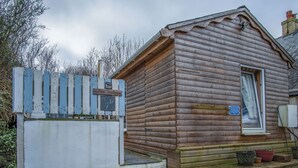 Eine Holzhütte mit einer kleinen Veranda, einem Fenster mit Vorhängen und einem Schild.