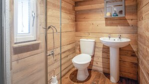 Ein Badezimmer mit Holzwandverkleidung, Toilette, Waschbecken und Dusche.