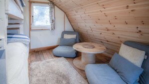 A cozy attic bedroom with a sloped ceiling, a window, a bed, a sofa, and a small table. - The Pod - 1 Bedroom - Freshwest Beach Retreat (Pembroke)