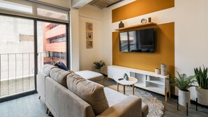 A modern living room with a sofa, a TV mounted on the wall, a small white table, and a potted plant. - Vivo One Zona 1 Guatemala (Guatemala City)