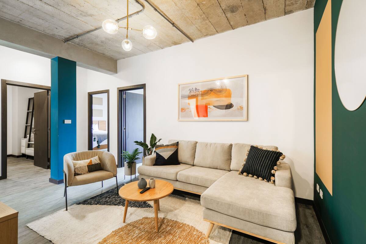 Un salon moderne avec un canapé, un fauteuil, une table basse et des œuvres d’art accrochées au mur.