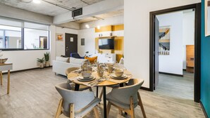 A modern living room with a dining area, a sofa, a TV, and a staircase leading to another level. - Vivo One Zona 1 Guatemala (Guatemala City)