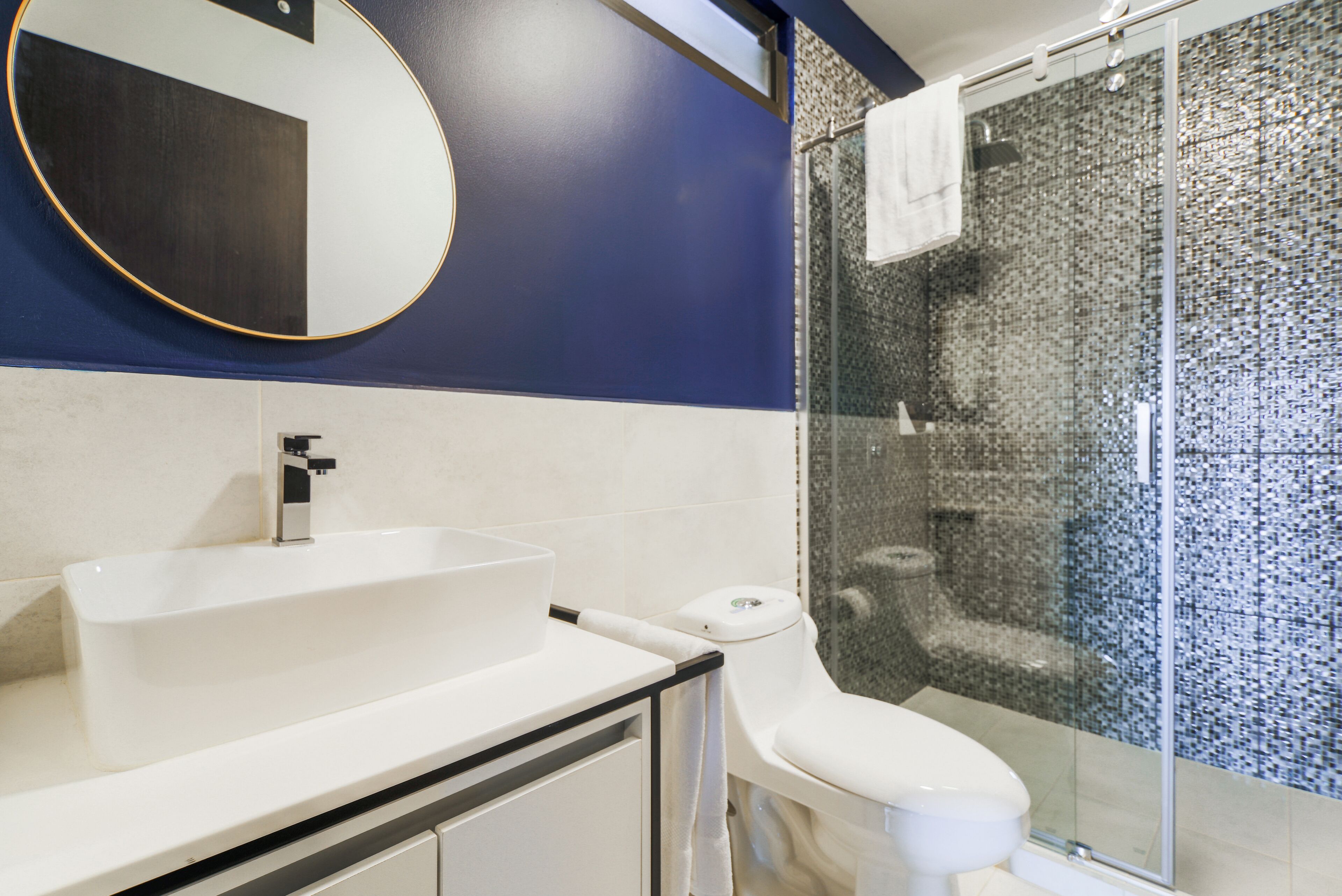 Un baño moderno con un lavamanos blanco, un inodoro y una cabina de ducha de vidrio.