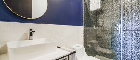 A modern bathroom with a white sink, a toilet, and a glass shower enclosure.