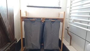 A wooden drying rack with two grey towels hanging.