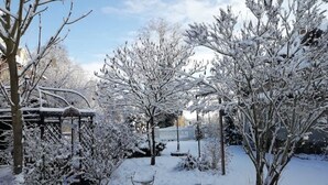 A snow-covered garden with bare trees and a gazebo.