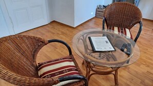 A room with wicker chairs, a glass table, and a remote control. - Ehemalige Bibliothek: Küche Kamin Netflix Hofladen (Steinhöfel)