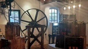 A rustic interior with a large wooden wheel, wooden crates, and vintage kitchen equipment. - Ehemalige Bibliothek: Küche Kamin Netflix Hofladen (Steinhöfel)