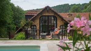 Ein Steinhaus mit großem Fenster und einem Pool im Vordergrund.