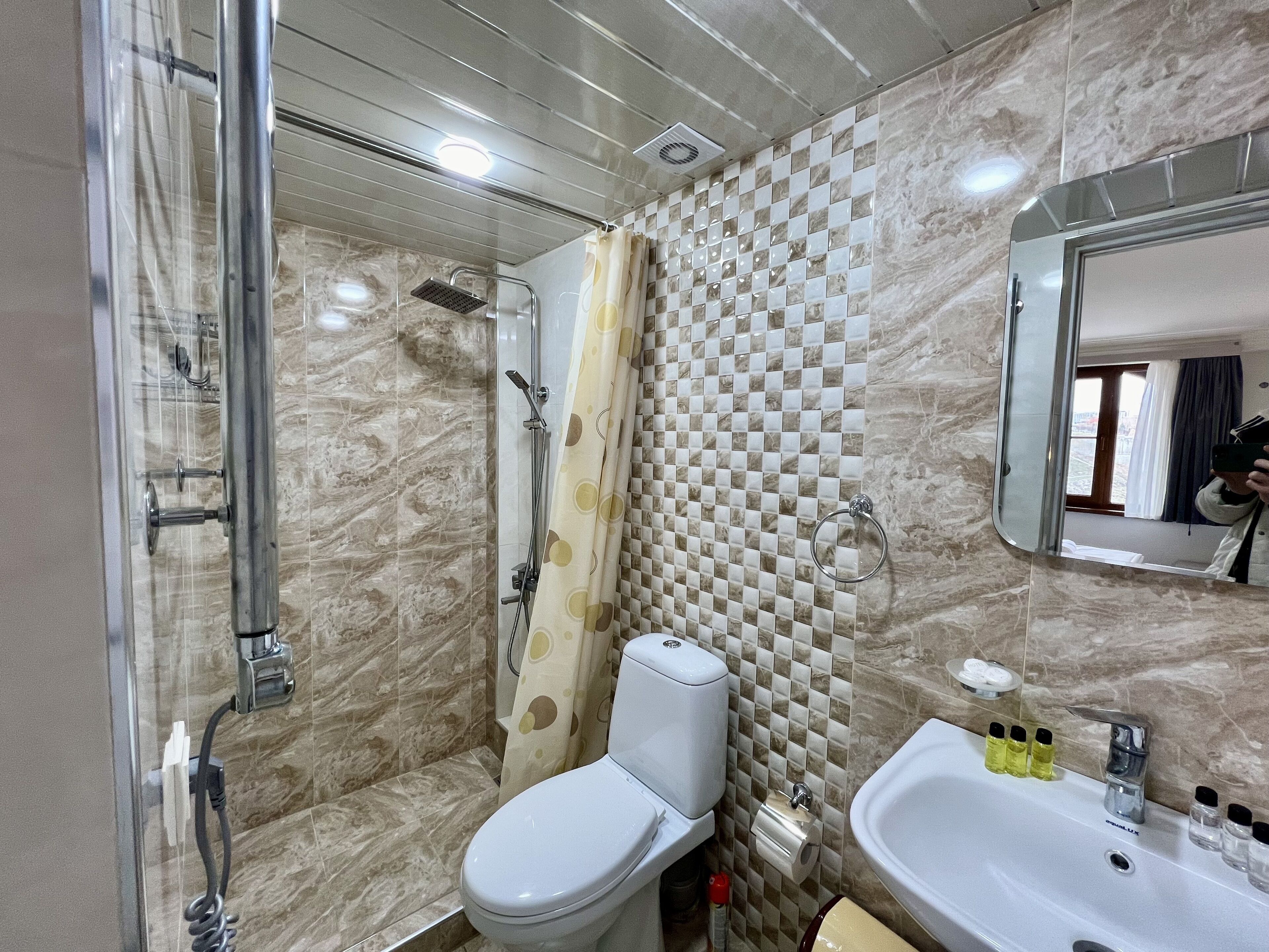 Un baño con ducha, inodoro, lavamanos y espejo.