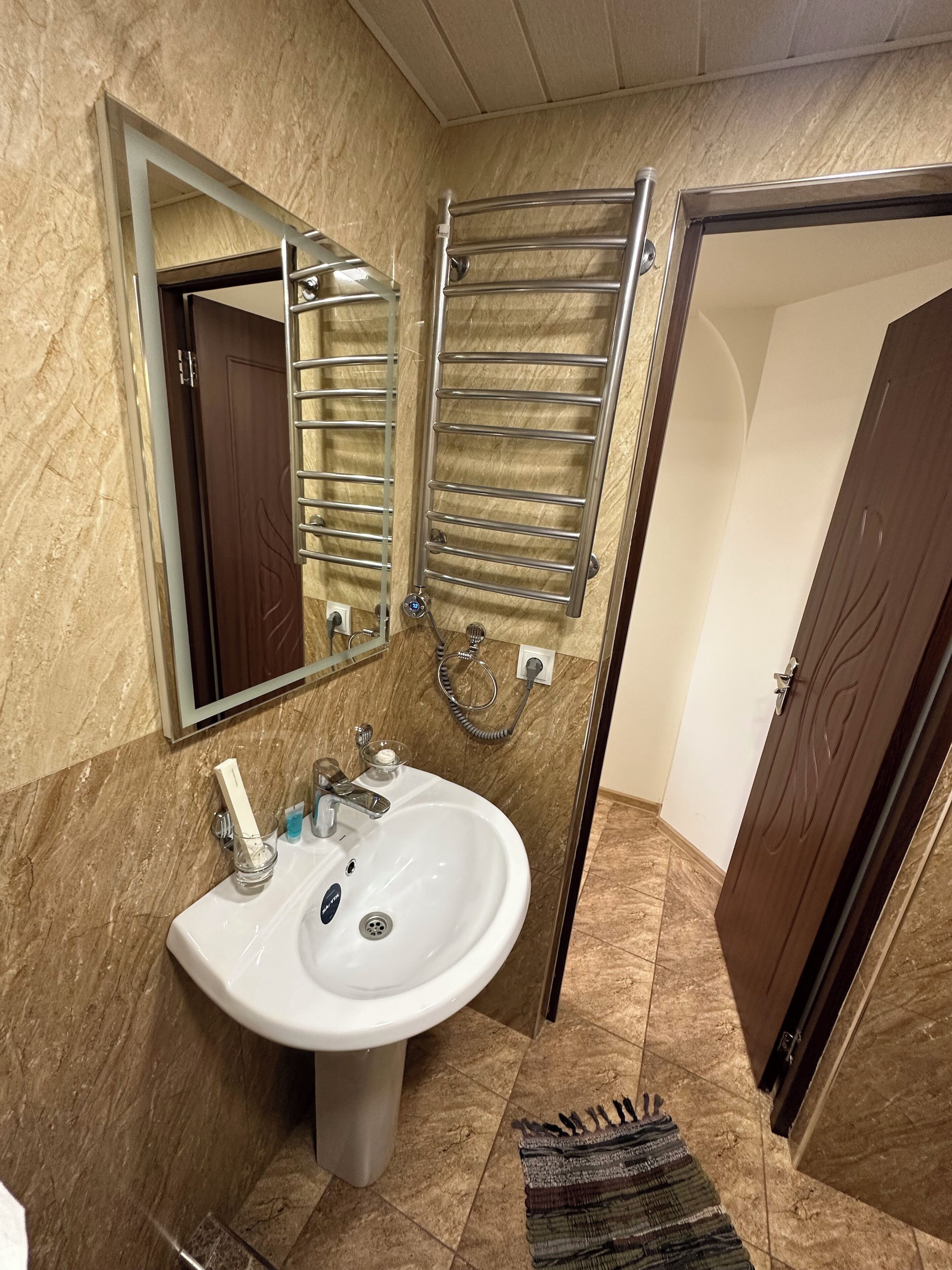 A bathroom with a white sink, a mirror, a towel rack, and a shower area.