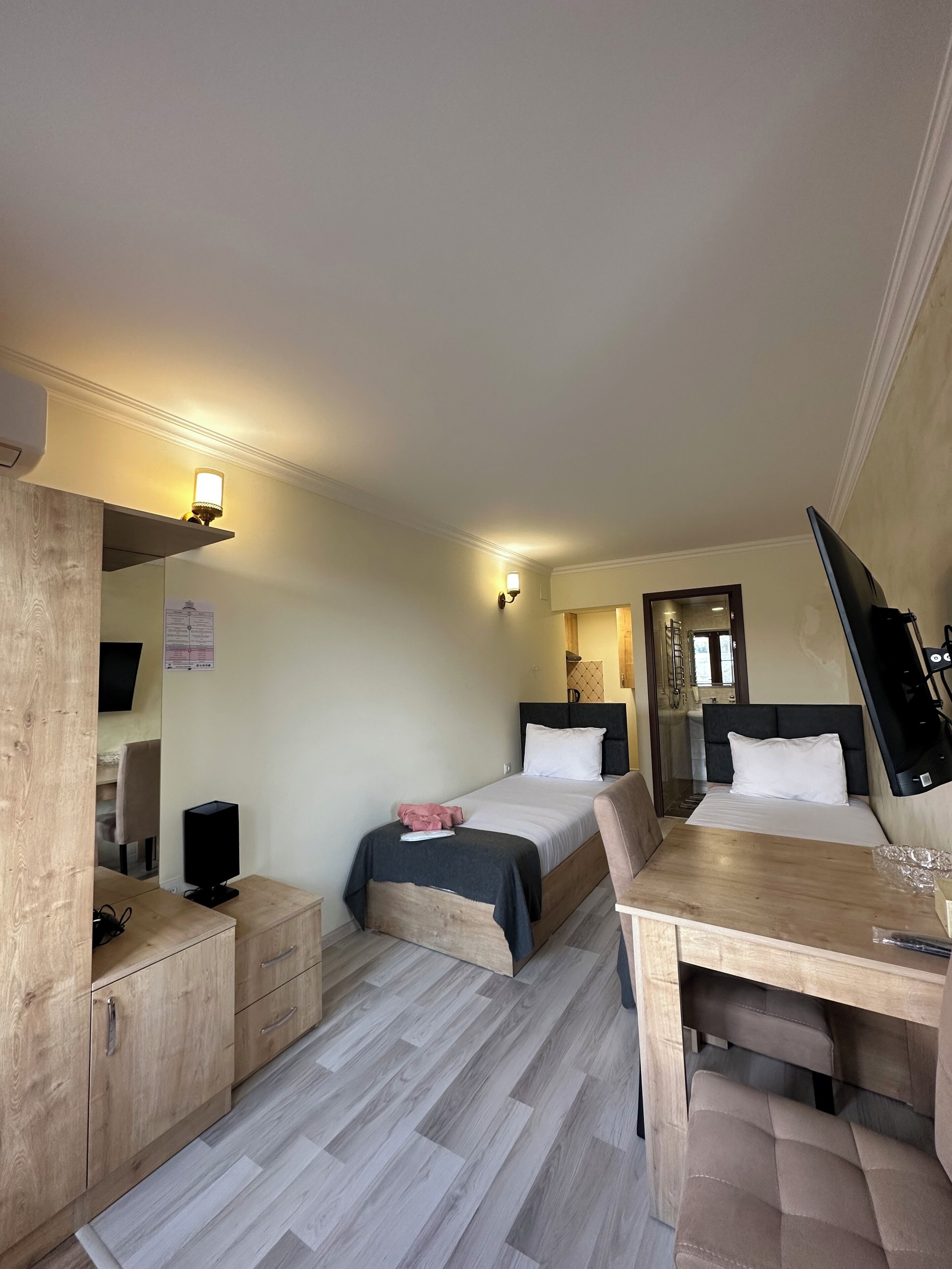 Una camera d'albergo con due letti, una scrivania, una televisione e uno specchio.