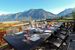 An outdoor dining area with a table set for 10, overlooking a mountainous landscape. - Chalet Kala (Risoul)