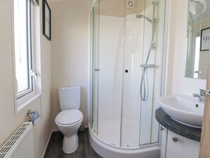 A modern bathroom with a glass-enclosed shower, a white toilet, and a sink with a marble countertop.