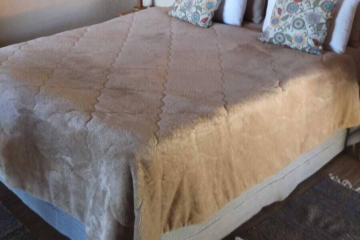 Ein Schlafzimmer mit einem großen Bett, einer Holzbalkendecke, einem gerahmten Bild an der Wand und einer Nachttischlampe.