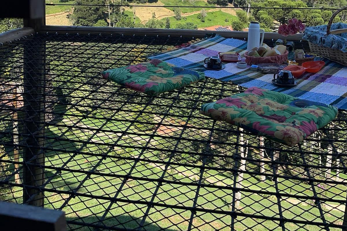 Eine Hängematte auf einem Balkon mit Blick auf eine grüne Landschaft aus Bäumen und Hügeln.