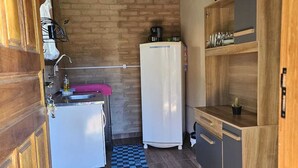 A compact kitchen with a refrigerator, a sink, and wooden cabinets. - Canto dos Pássaros (Santo Antonio do Pinhal)