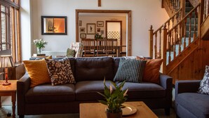 A cozy living room with a brown leather sofa, wooden coffee table, and a staircase with wooden railings. - Wheelhouse (Barnstaple)