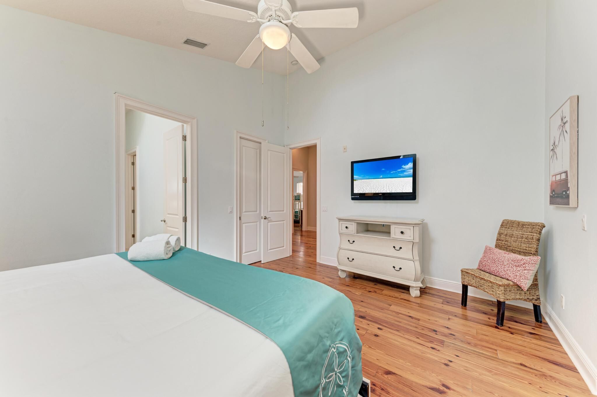 A bedroom with a bed, a television, a chair, and a dresser.
