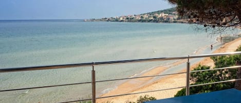 A balcony with a view of a beach and the sea.