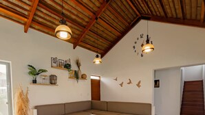 A modern living room with a sectional sofa, wooden flooring, and a ceiling with exposed beams. - HOP Praia Exclusiva Laguna y Playa en Chincha (El Carmen)