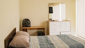 A bedroom with a bed, a bedside table, a desk, a chair, a dresser, and a mirror. - HOP Ohana Exclusiva en Campo y Playa en Chincha (El Carmen)
