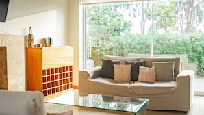 A living room with a glass coffee table, a beige sofa with multiple cushions, a wooden cabinet, and a fireplace. - HOP Ohana Exclusiva en Campo y Playa en Chincha (El Carmen)