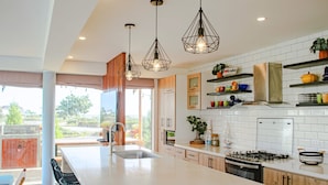 A modern kitchen with a large island, pendant lighting, and a view of the outdoors. - HOP Aruba Exclusiva Oasis y Playa en Chincha (El Carmen)